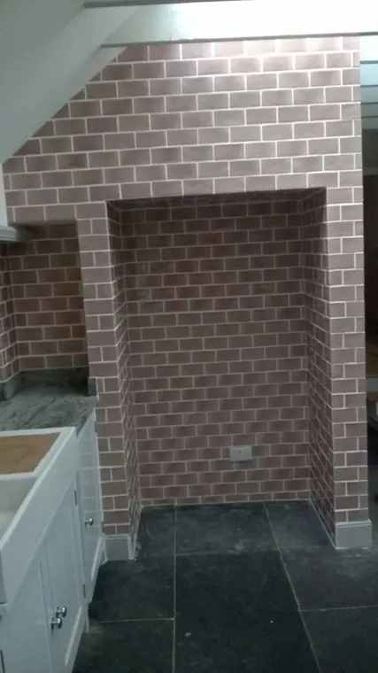 Brick-effect tiles lining the chimney alcove, each course lined through into the reveal.