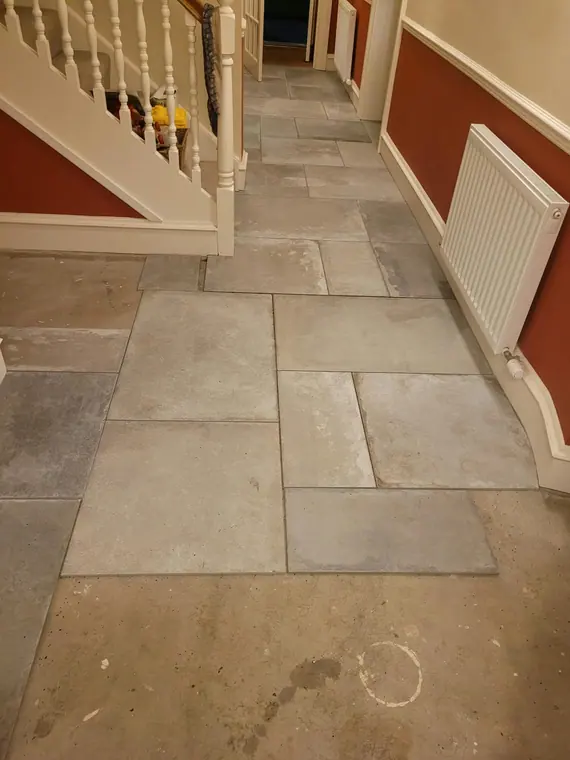 The floor at the foot of the stairs, laid to run square with the hall.