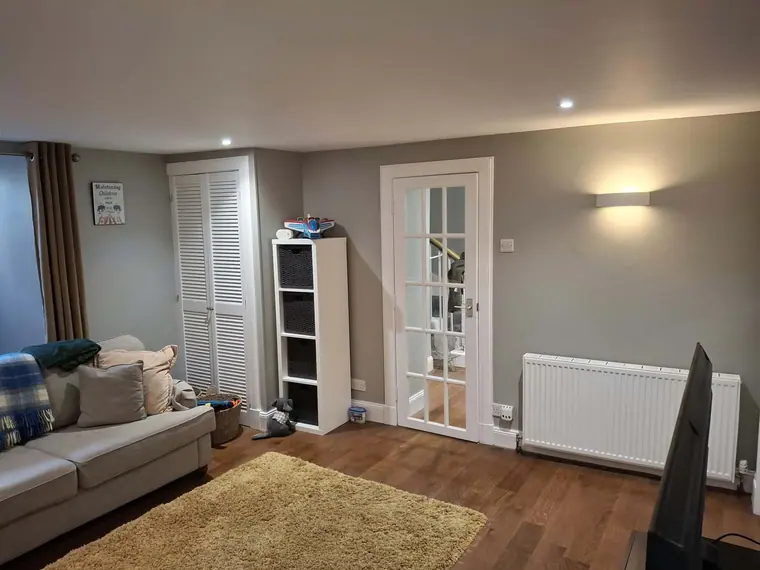 The finished living room: warm grey walls, white woodwork and a glazed door.
