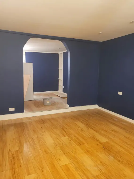 The back room in the same navy, with the arch framing the room beyond.