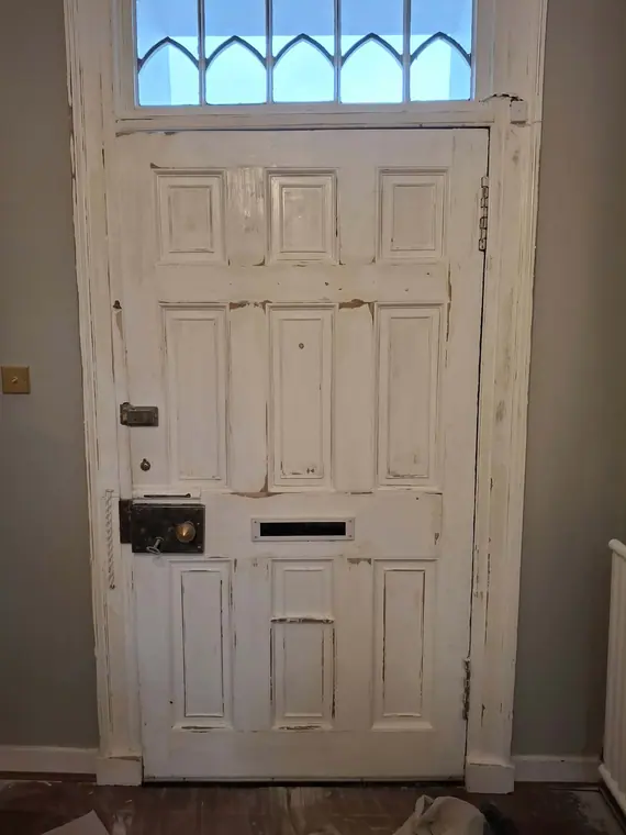 The six-panel front door before work: chipped paint, failed filler and years of overpainting.