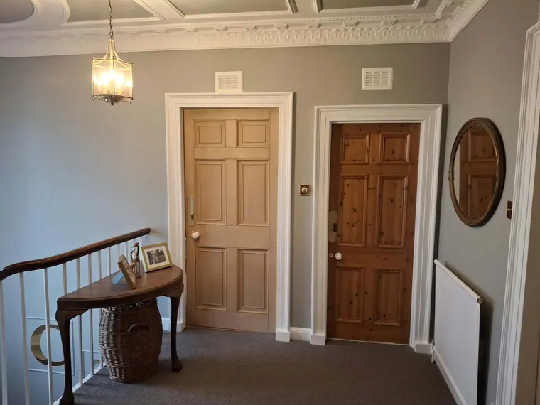 The upper landing with the ornate cornice picked out in white above freshly painted walls.