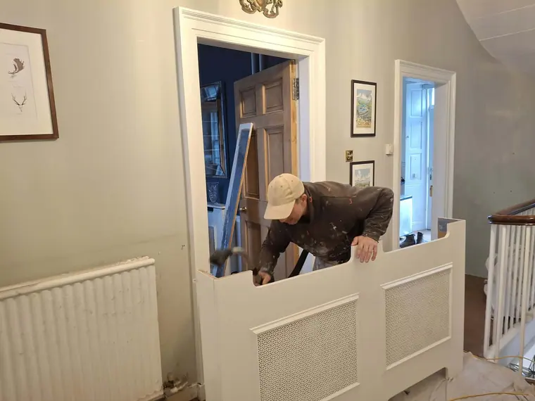 Fitting a panelled radiator cover on the landing.